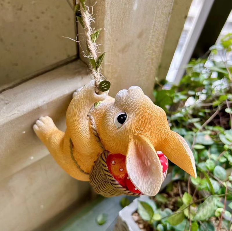 Rabbit figurine mid-climb on a wall edge with leaves and vines