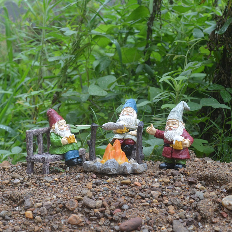 Gnome figures and campfire set in a garden bed
