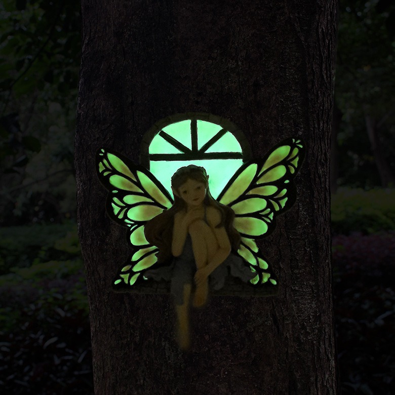 Fairy window glowing green in the dark on a tree trunk