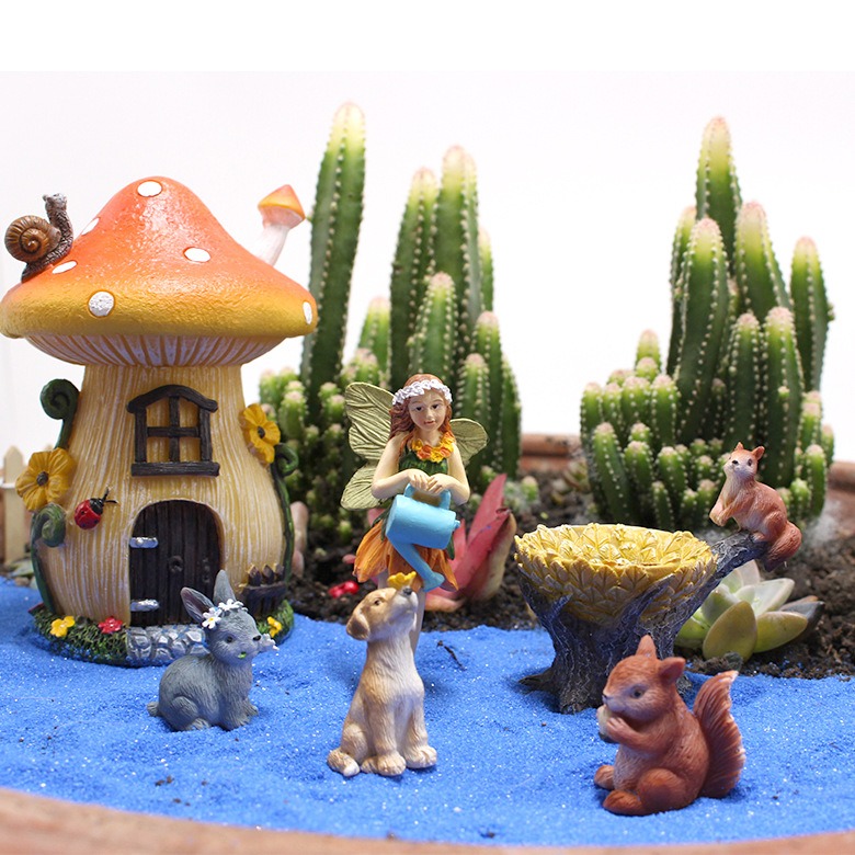 Mushroom house and figures in a cactus garden on blue sand