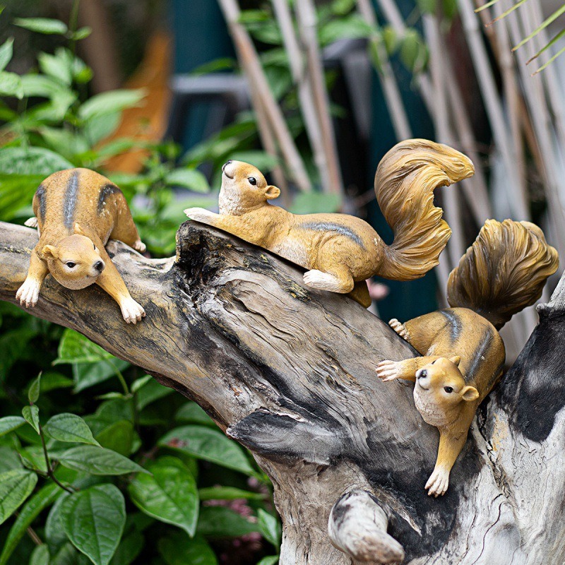 Several resin squirrels perched on a driftwood branch in a leafy garden