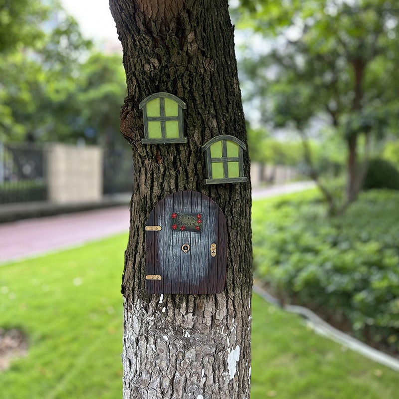 Fairy door and windows on a tree in an outdoor park with grass