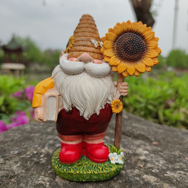 Gnome statue on a stone ledge among green shrubs and pink flowers