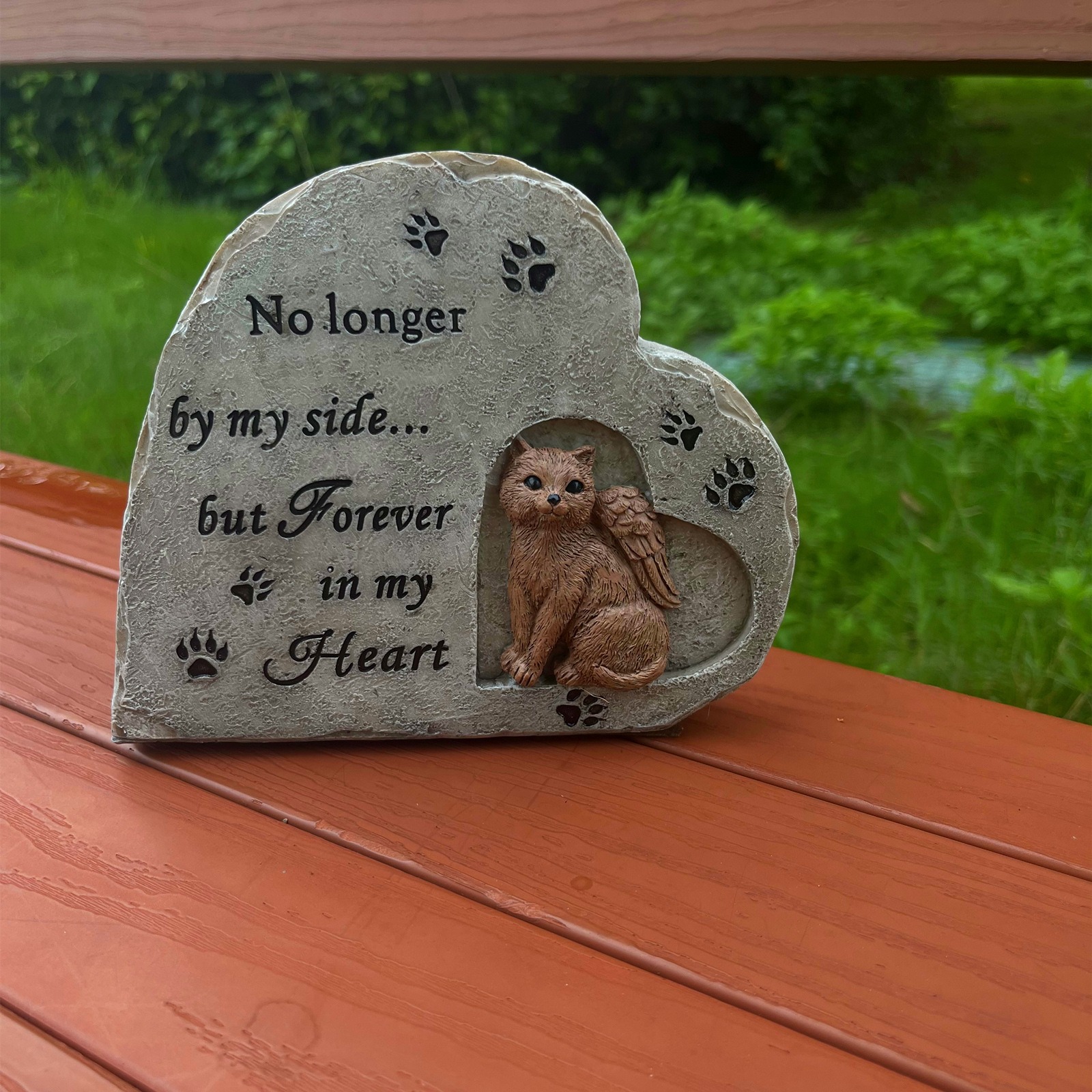 Cat memorial stone resting on a wooden deck with green garden behind it