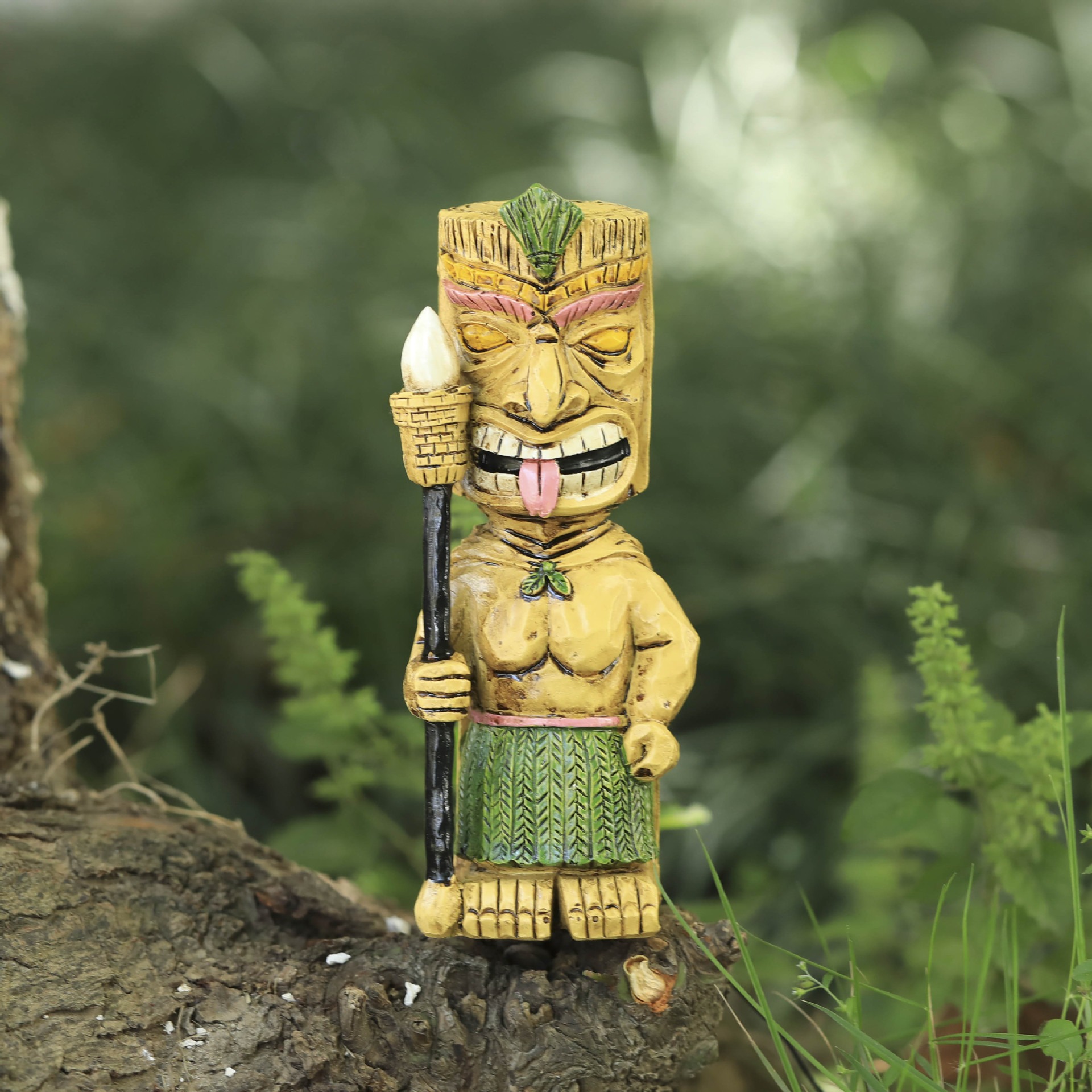 Tiki totem perched on a tree log among ferns and grass