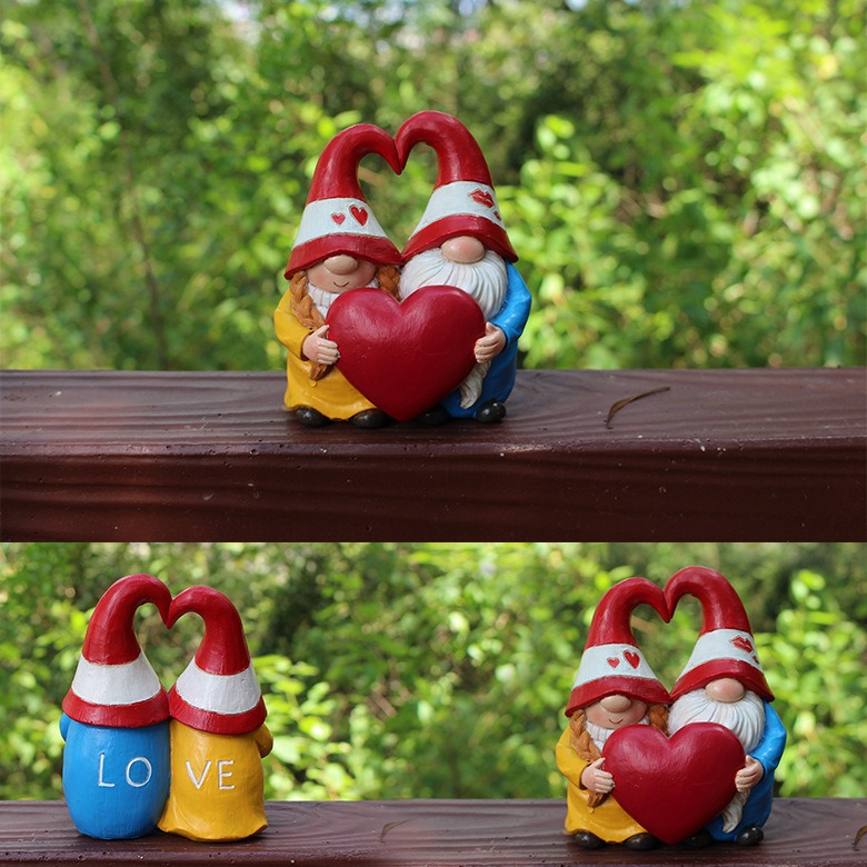 Gnome couple on a wooden ledge against green foliage