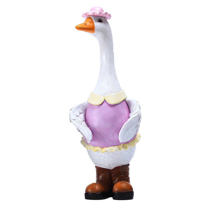 White resin goose with painted pink hat and lilac dress standing outdoors