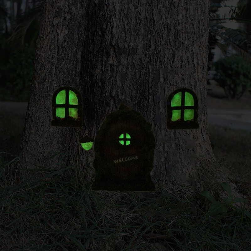 Glowing fairy door and windows lit green on a tree trunk