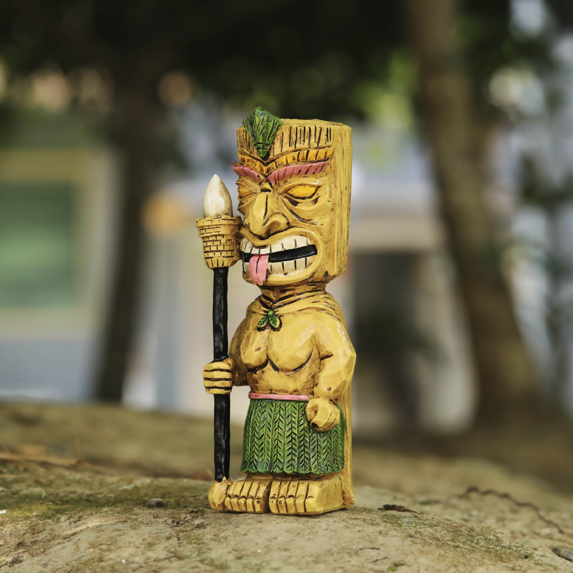 Tiki totem placed on a mossy stone in a blurred outdoor garden