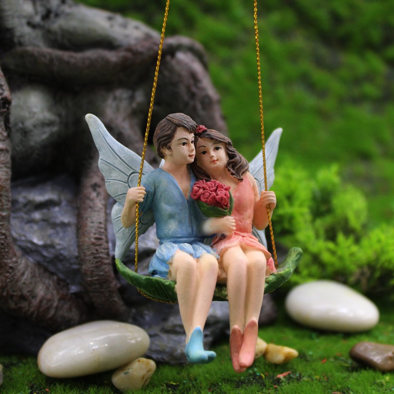 Close-up of fairy couple swing among moss and stones with wings visible