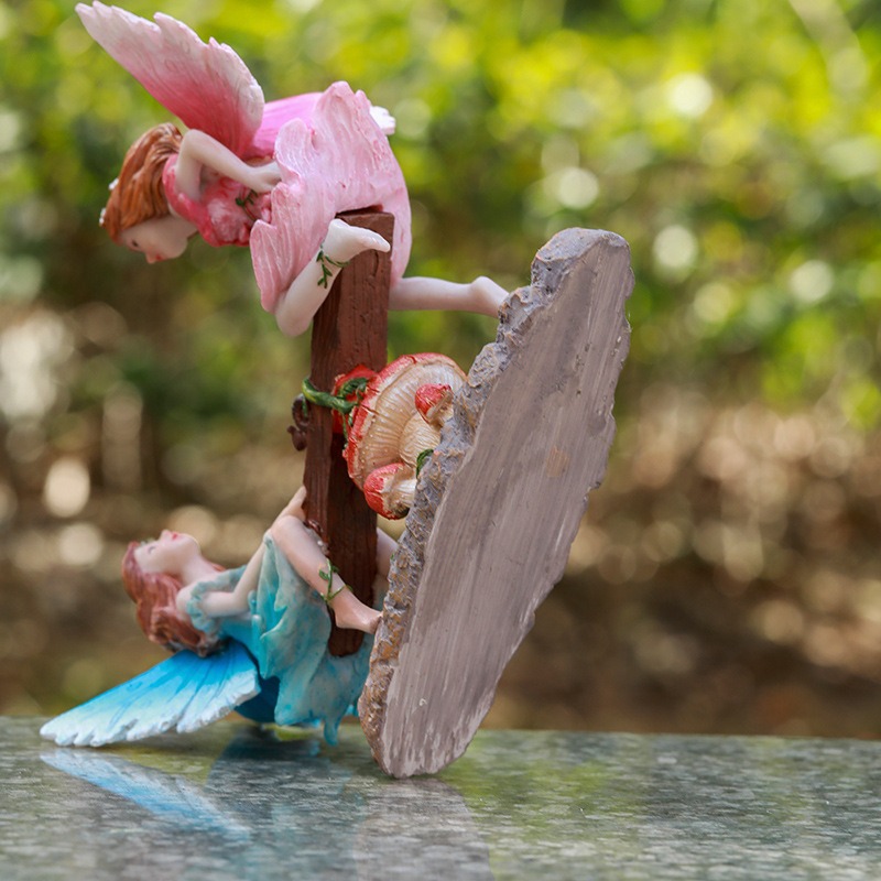 Hand-painted fairy figurine resting among outdoor garden greenery