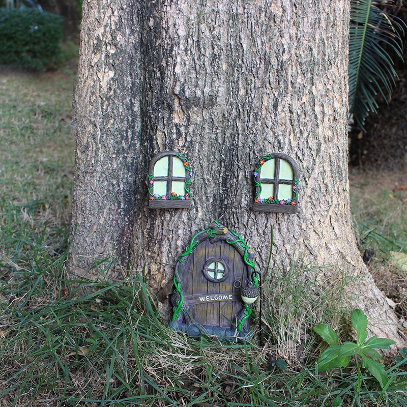 Fairy door and windows mounted on a tree trunk in daylight