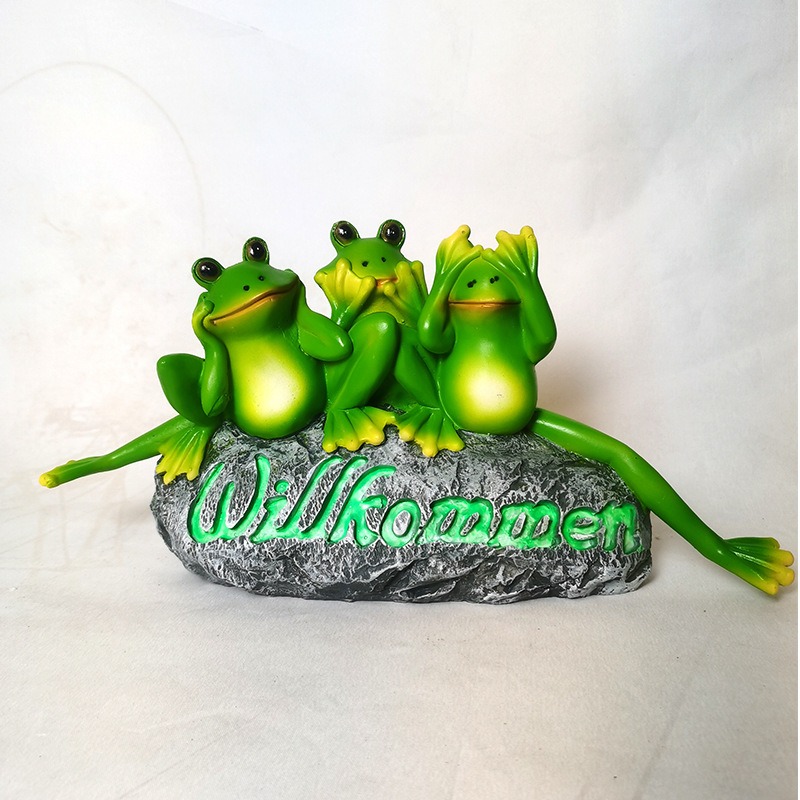 Front view of the Willkommen frog sign on a light backdrop