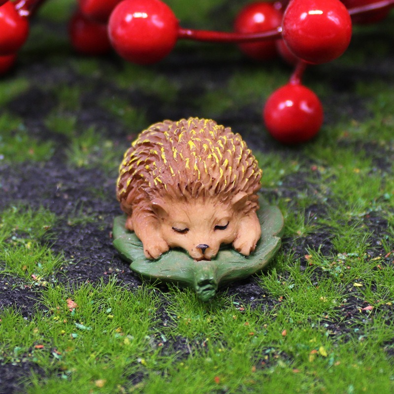 Hedgehog figurine on moss beside a red berry sprig