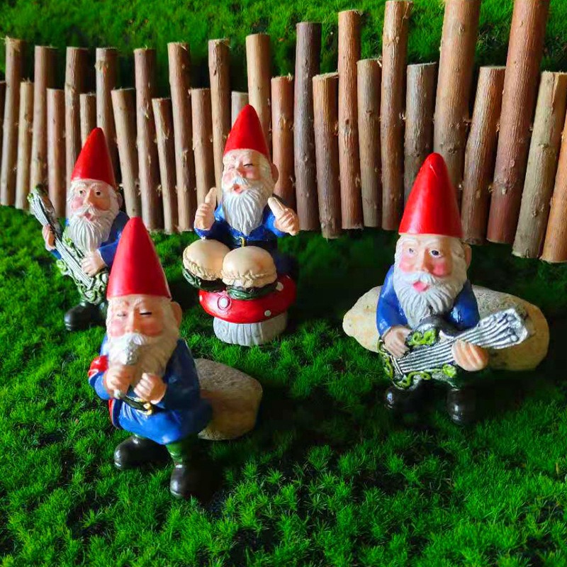 Gnome figurines among moss and a wooden fence in a garden