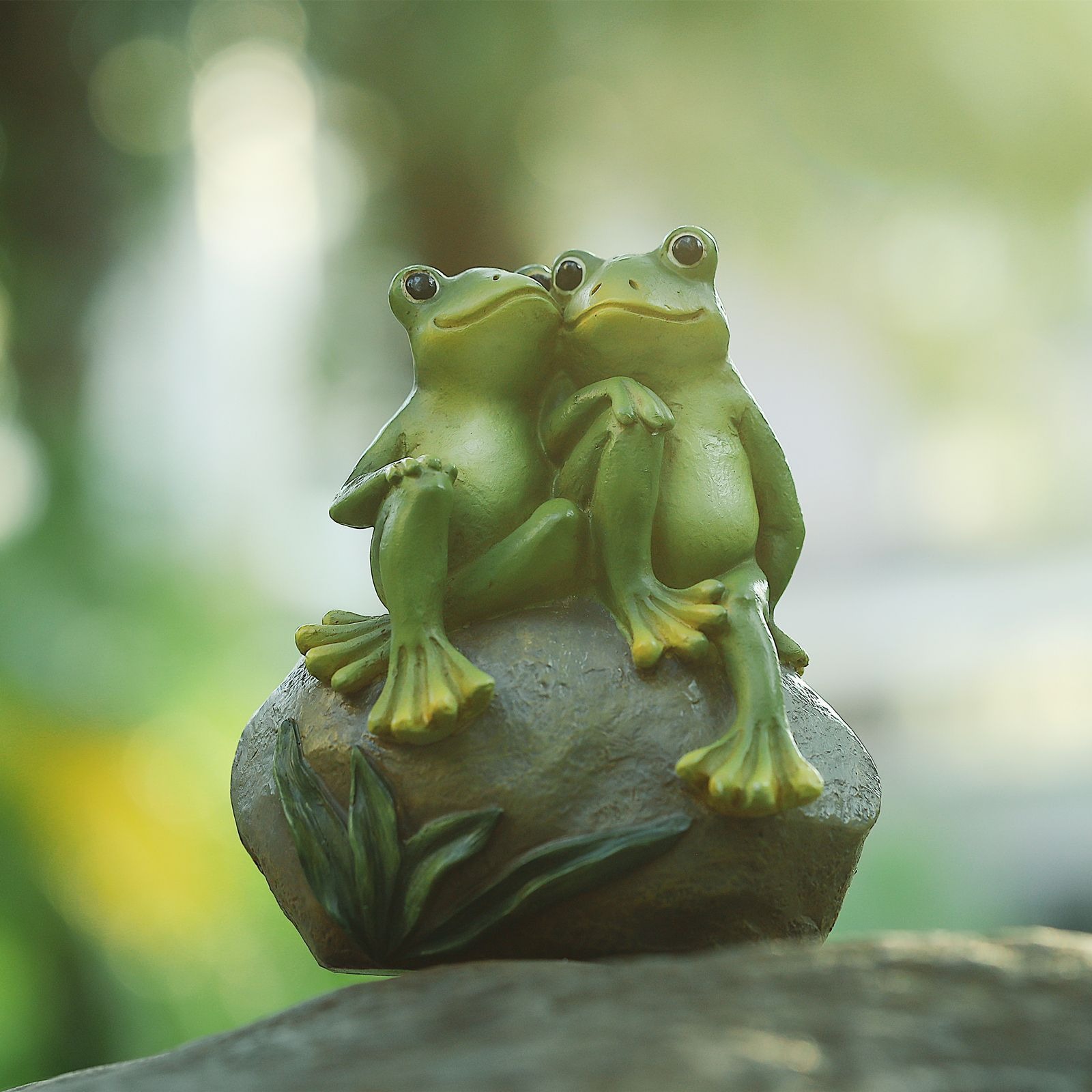 Two frogs embracing on a rock base among garden greenery