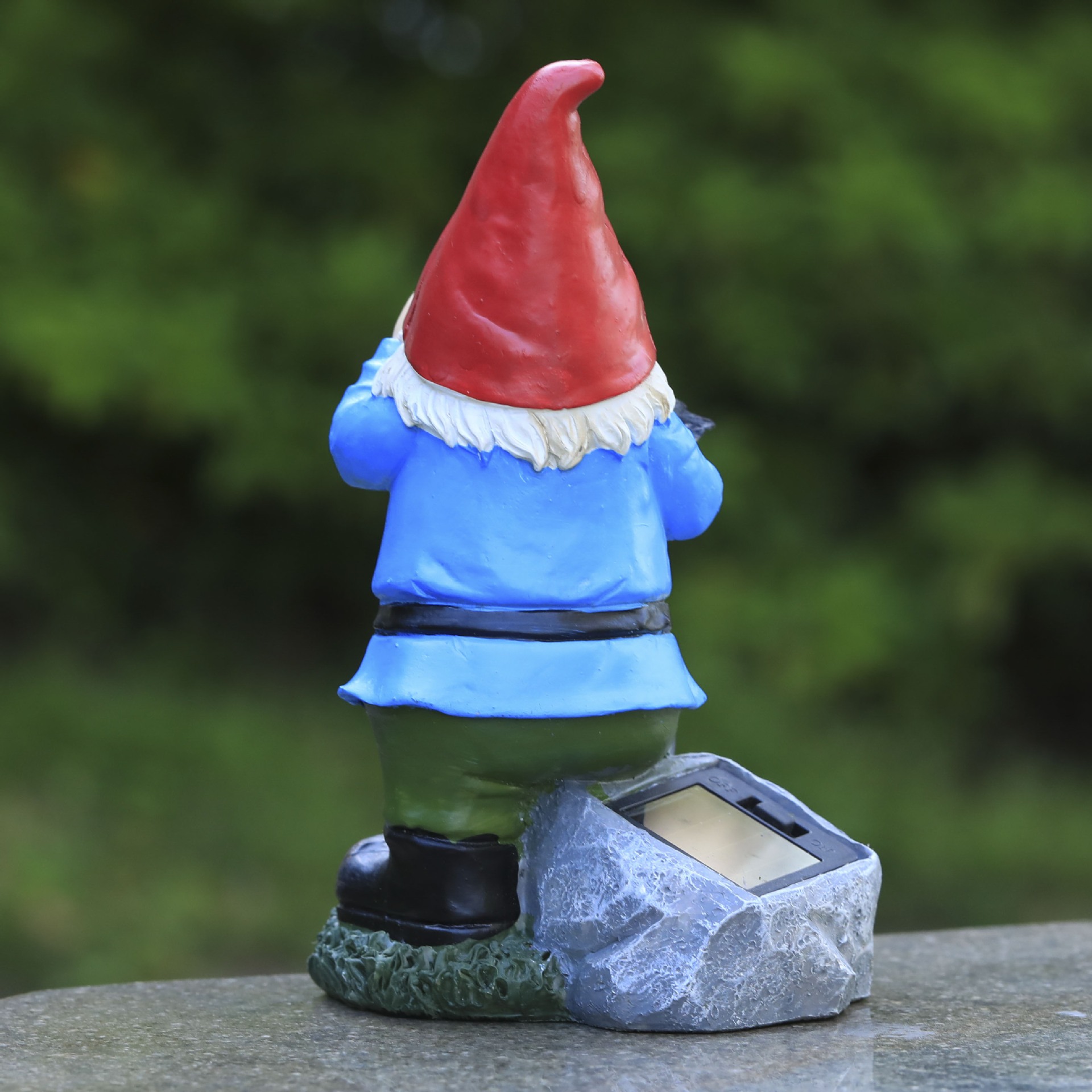 Back view of gnome with solar panel in faux-stone base on a ledge