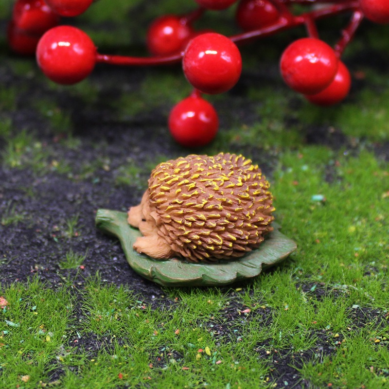 Side view of hedgehog figurine on leaf base set among moss