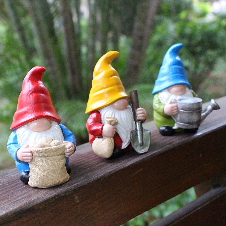 Gnomes perched on a wooden rail among leafy plants