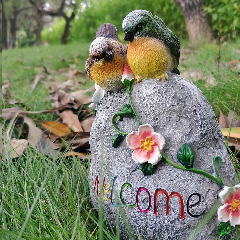 Welcome stone placed on grass with lettering and flowers visible