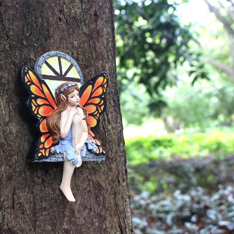 Fairy window pendant on a garden tree trunk in daylight