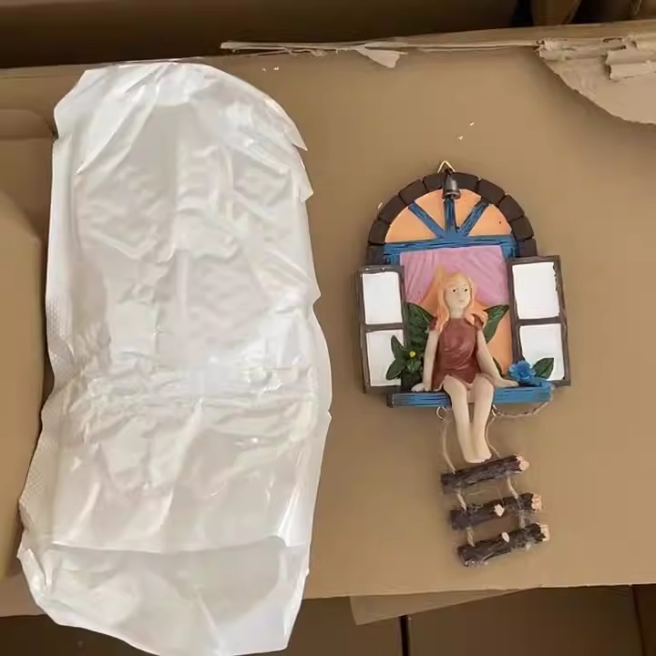 Resin fairy window decoration hanging on a garden wall