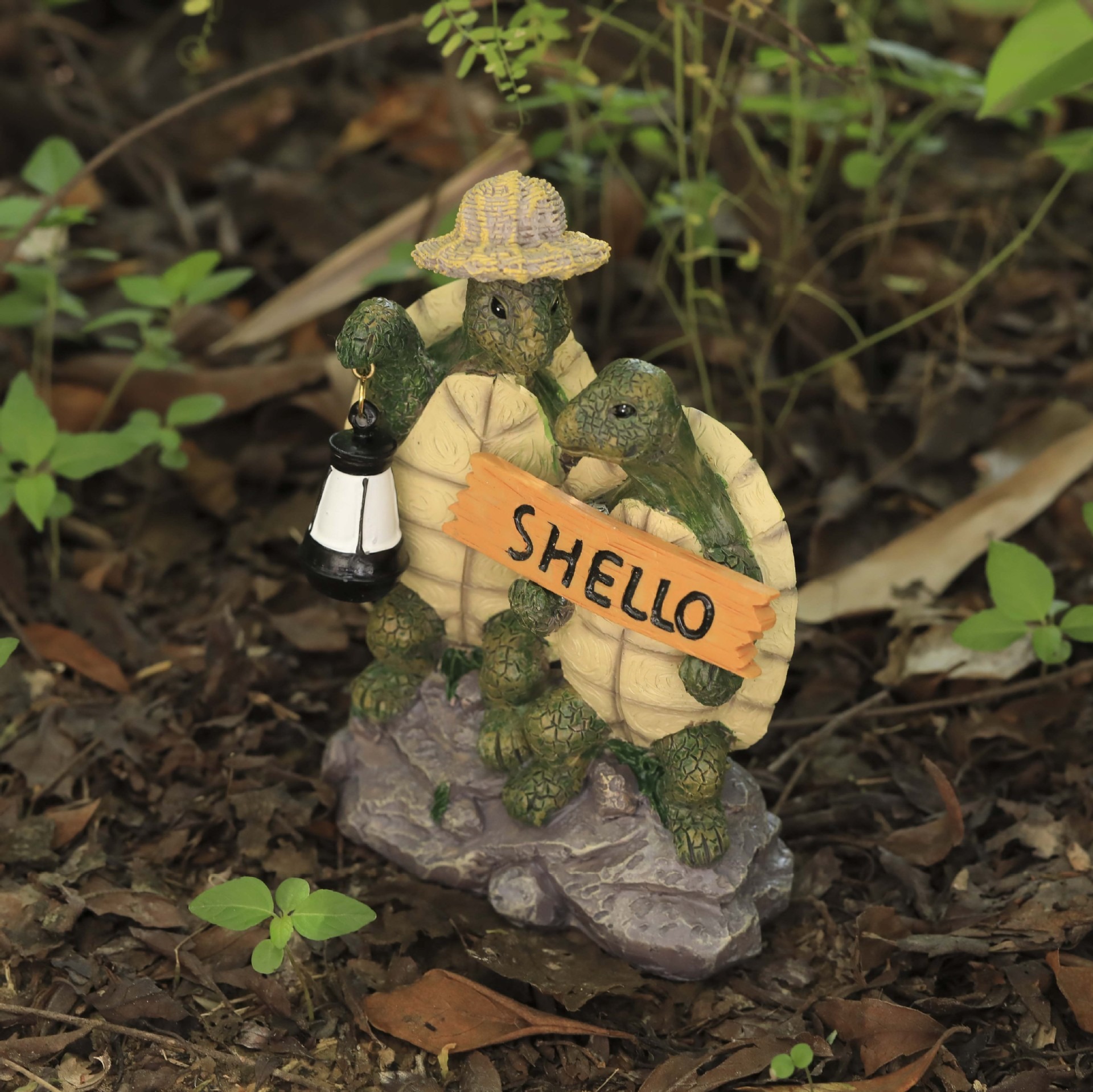 Turtle couple figurine set in soil among dry leaves on forest floor