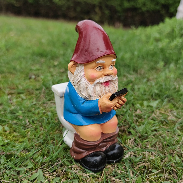 Gnome on a toilet set on green grass in a garden