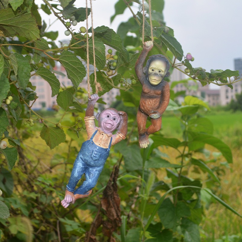 Resin monkey clinging to a branch in a leafy backyard