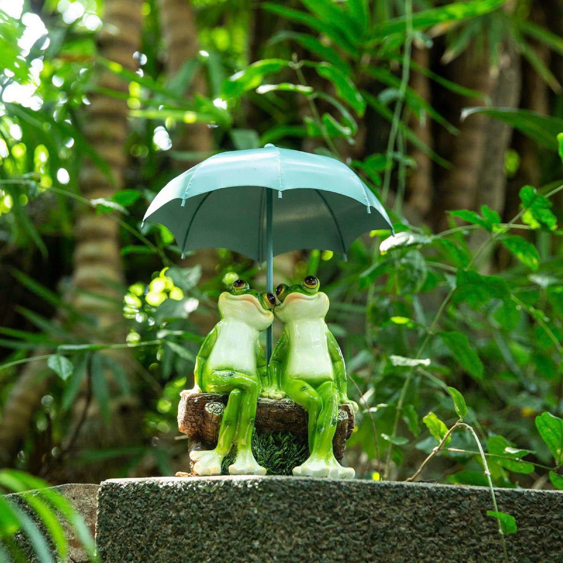 Frog umbrella figurine placed among green foliage on a stone ledge
