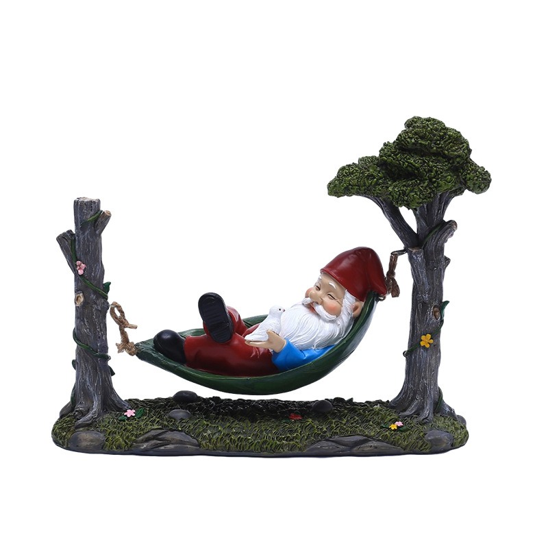 Sleeping garden gnome in a hammock between sculpted tree trunks