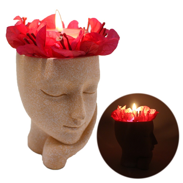 Face planter holding a lit candle with red bougainvillea around it