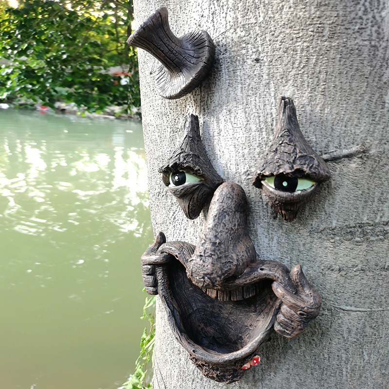 Tree face ornament on a trunk beside a pond with greenery