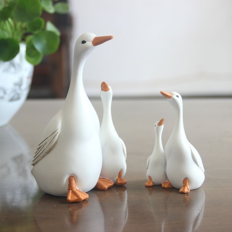 Mother and child duck figurines in a garden setting with copper accents