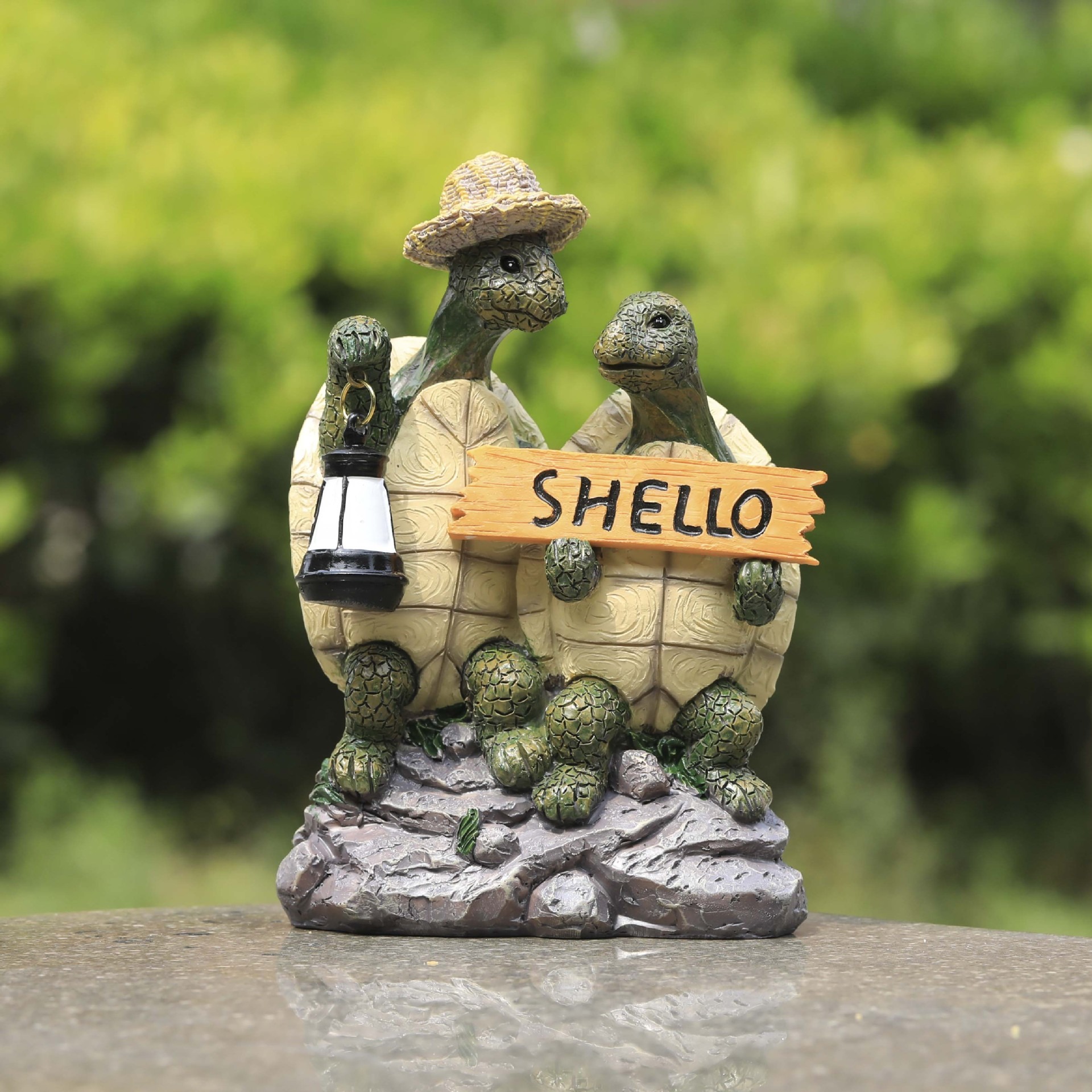 Turtle couple figurine standing on a stone surface among green foliage