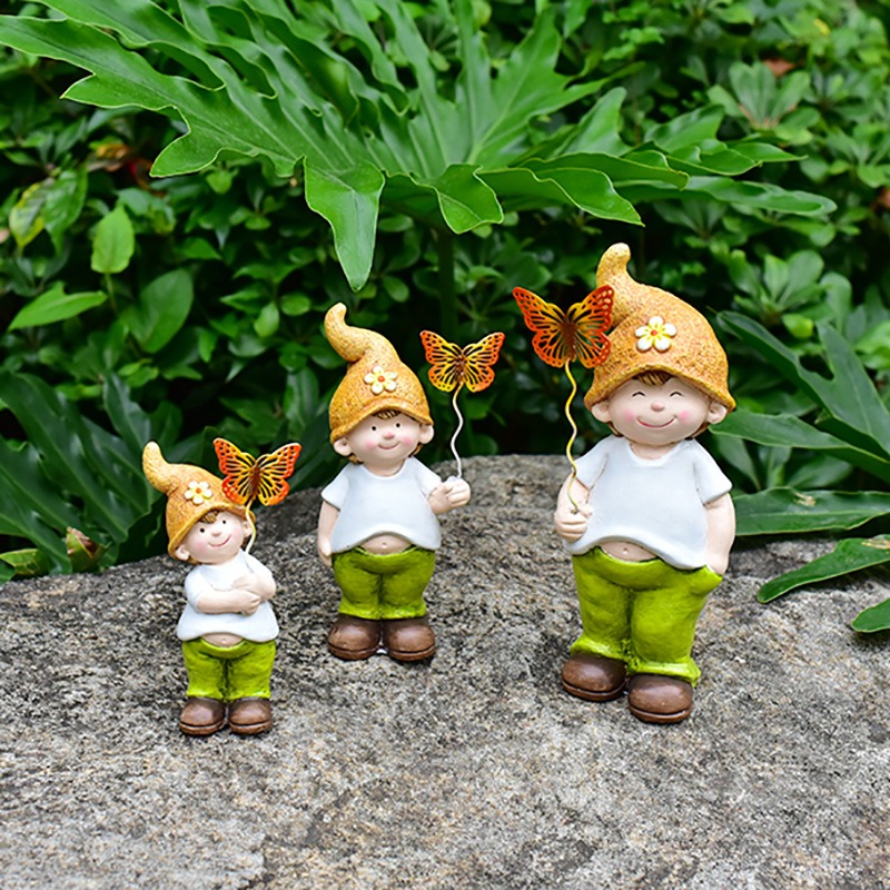 Garden dwarf trio sitting on a rock among green foliage