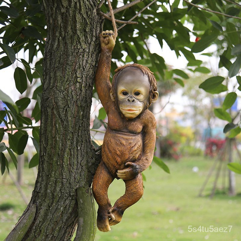 Resin monkey clinging to tree trunk with natural rope