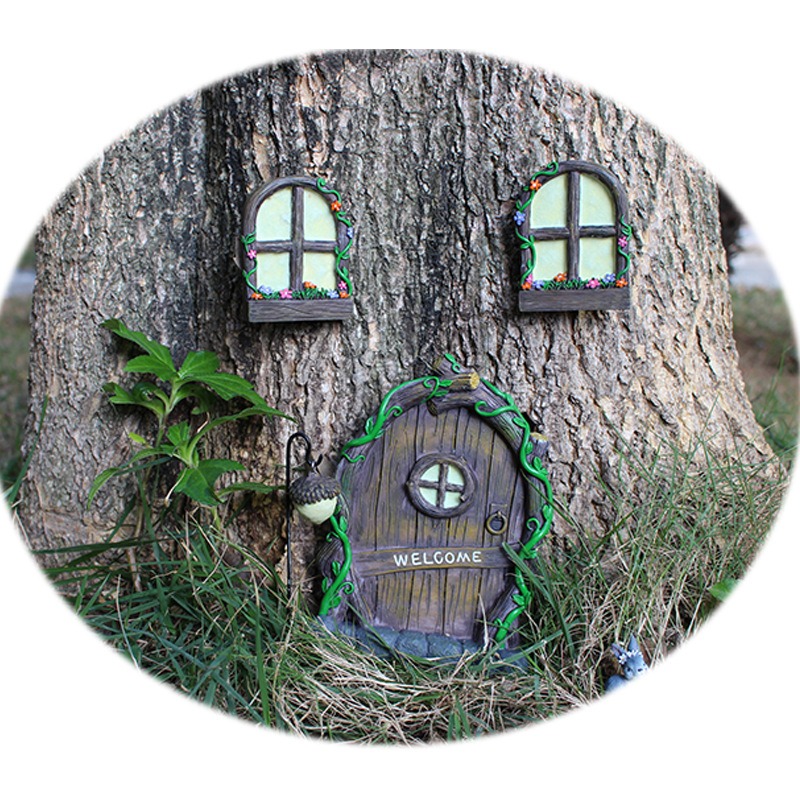 Fairy door, windows and acorn lantern arranged on a tree trunk