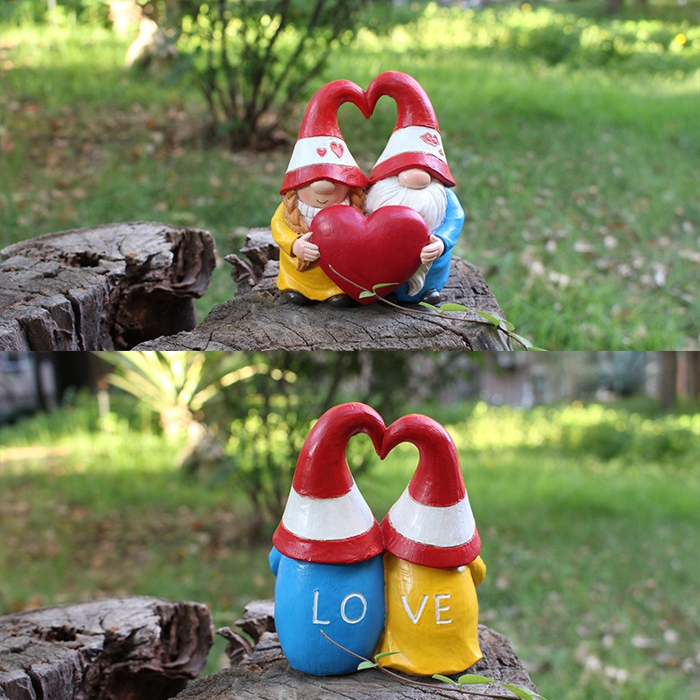 Gnome couple placed on a tree stump in a grassy garden