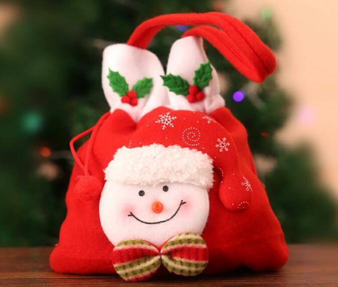 Red drawstring bag with plush character face beside a festive tree