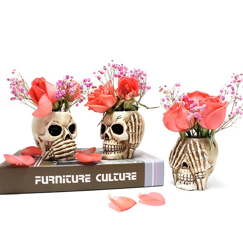 Skull planters holding pink roses and baby's breath on a styled shelf