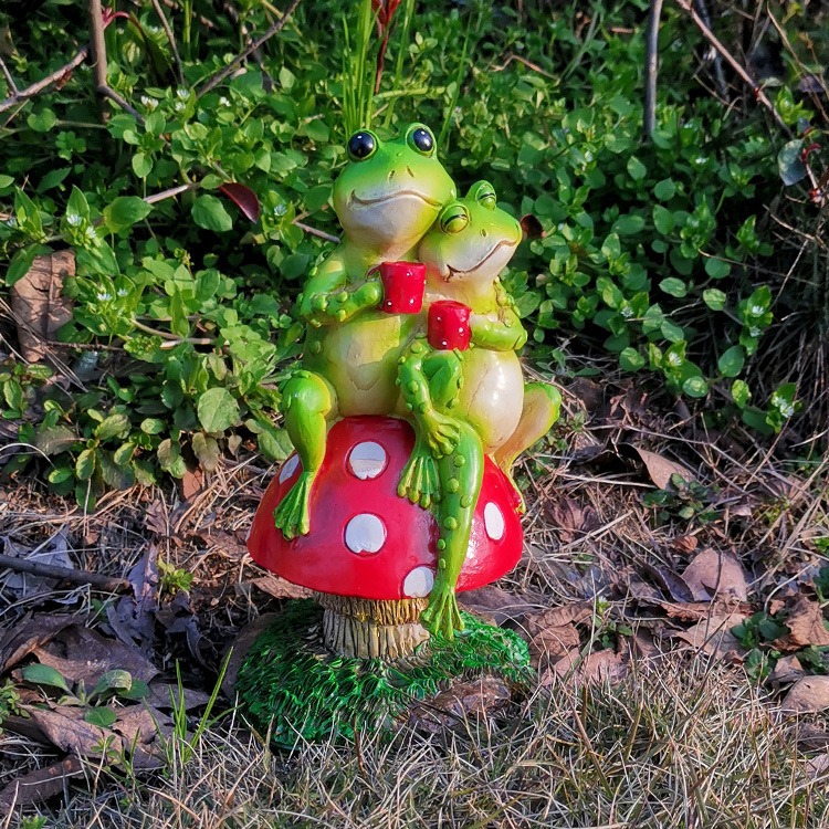 Frog mushroom garden figurine set among leaves and dry grass outdoors