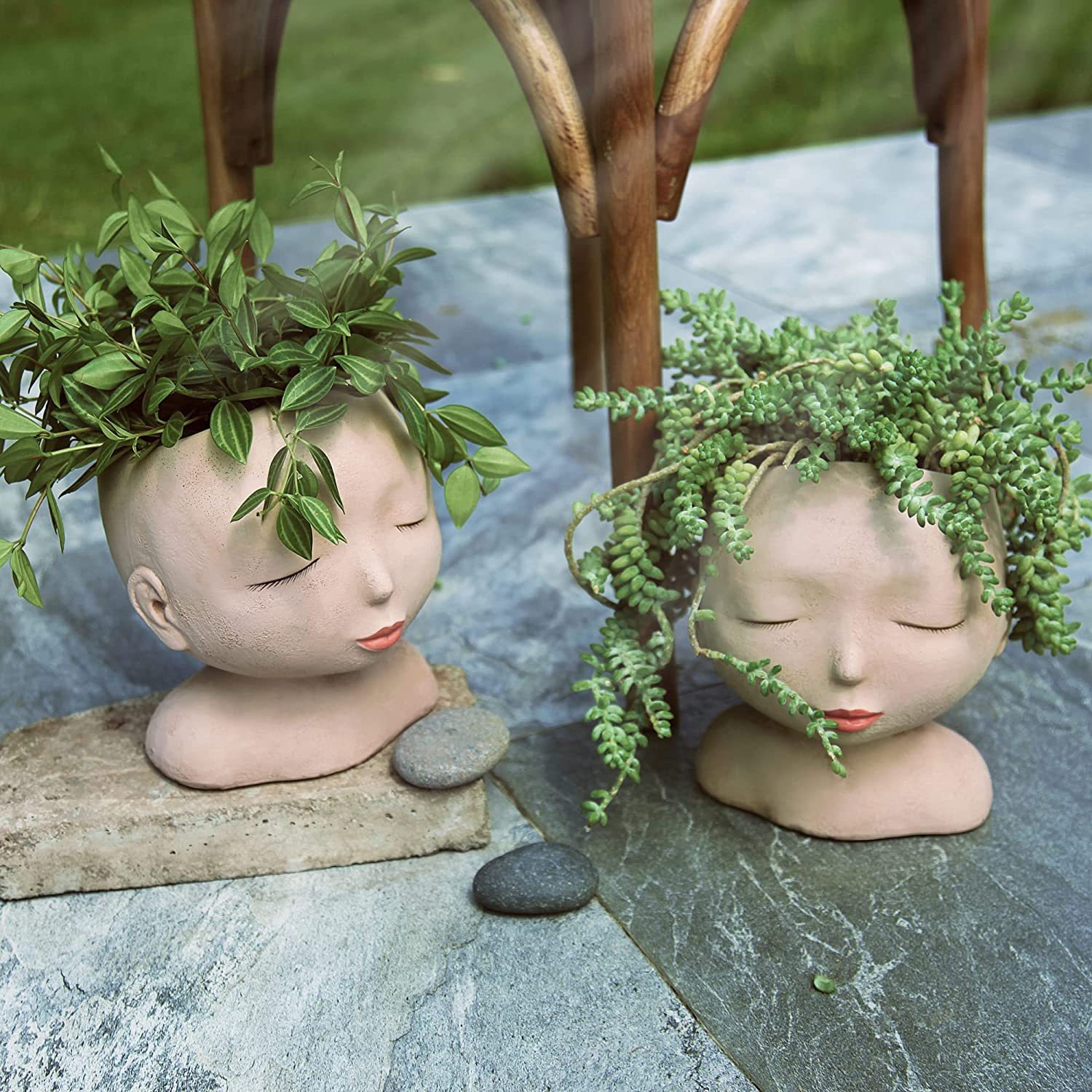 Two face planters on a slate patio with trailing vines draping over the heads