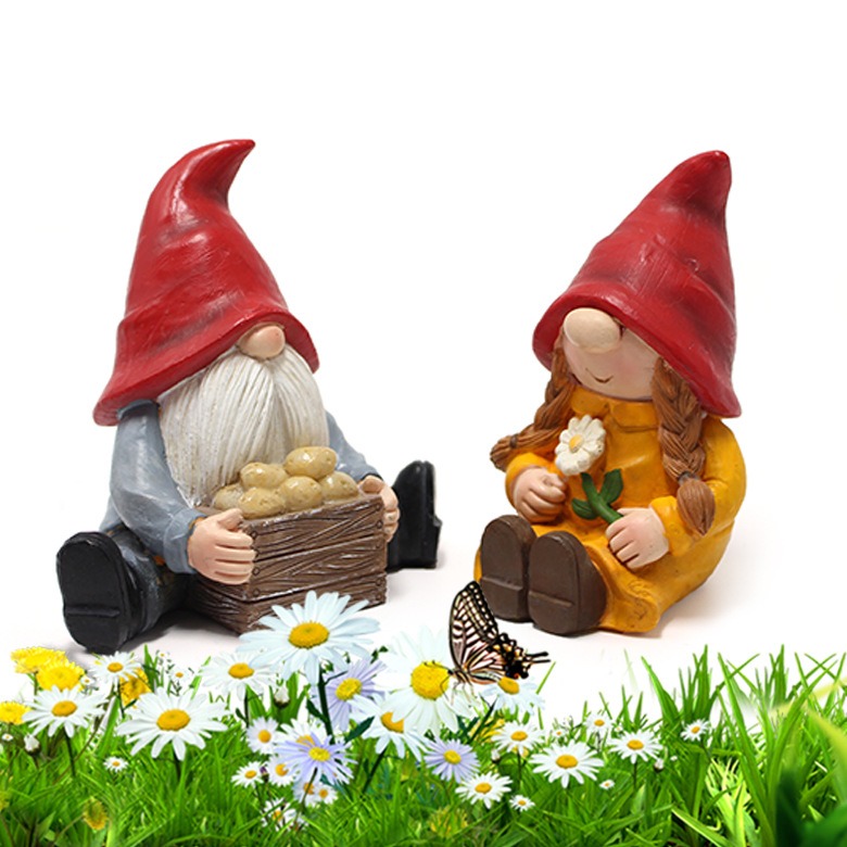 Gnome couple among daisies in a garden bed with a butterfly nearby