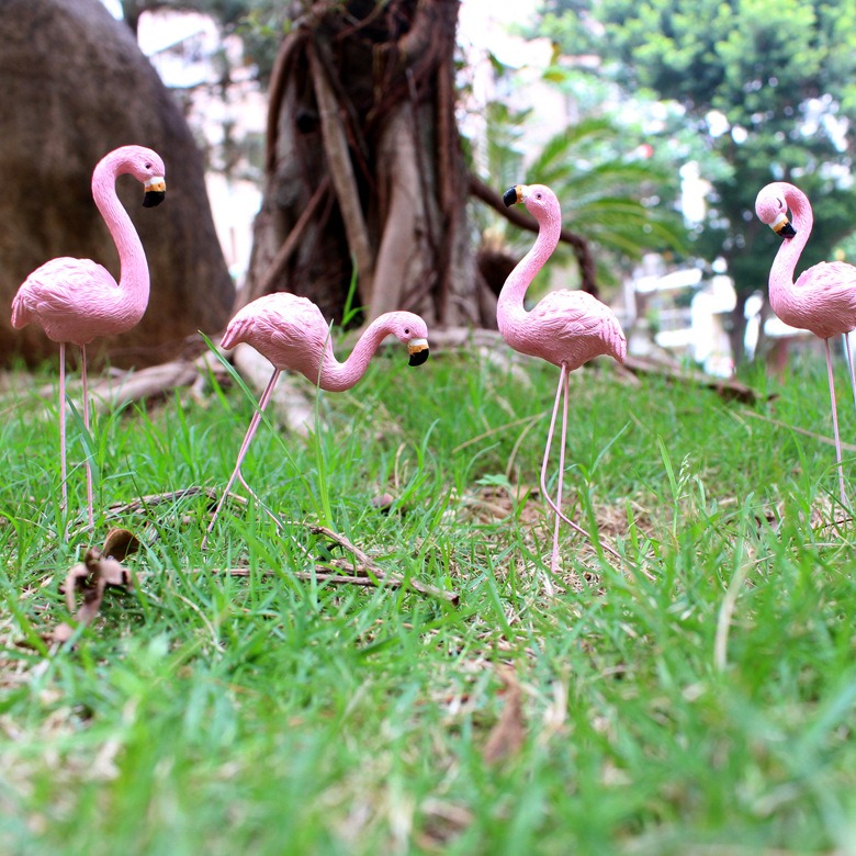 Pink flamingo garden stakes standing in green lawn grass
