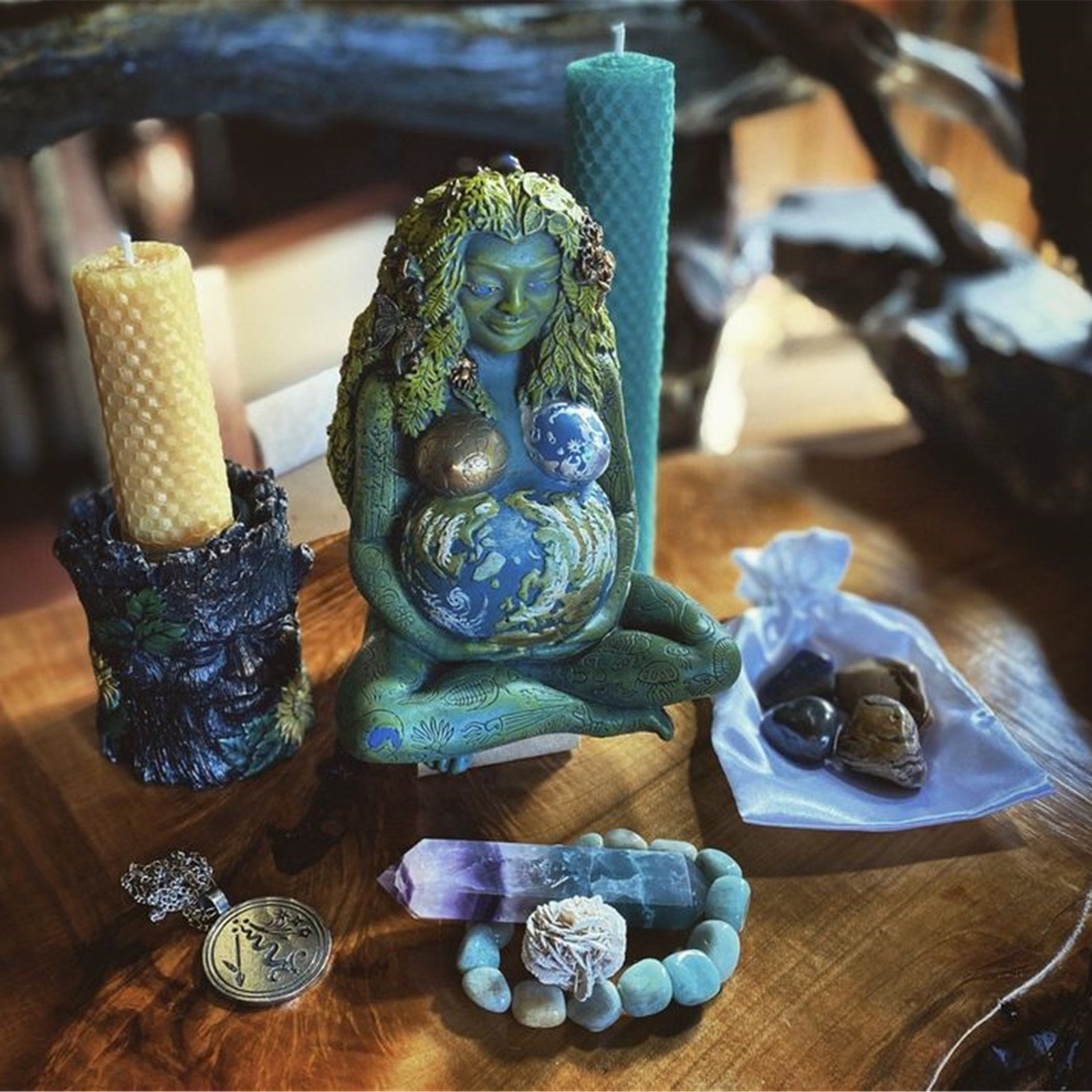 Gaia statue styled on a wooden table among candles and crystals