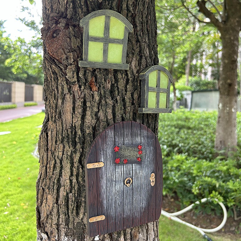Angled view of fairy door with two window panes on tree bark