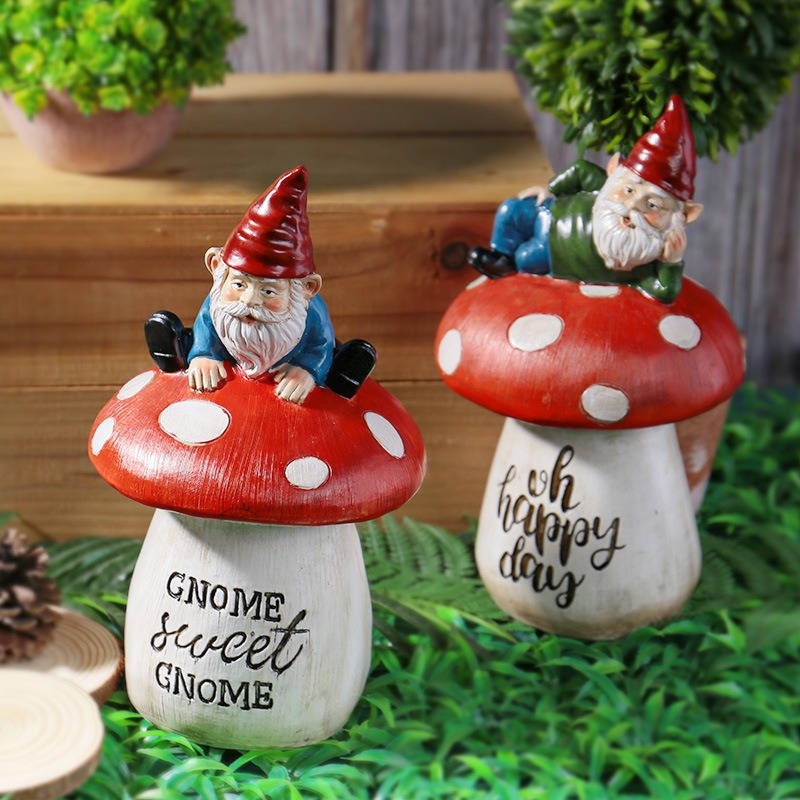 Two gnome mushroom statues on grass beside pinecone and wood slices