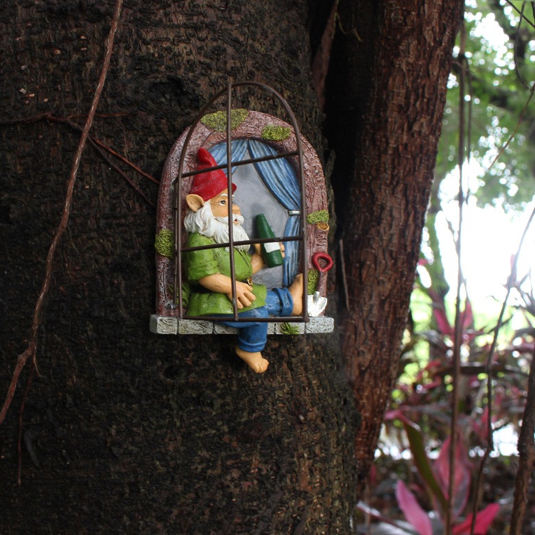 Gnome window with iron frame closed over the window on a tree trunk