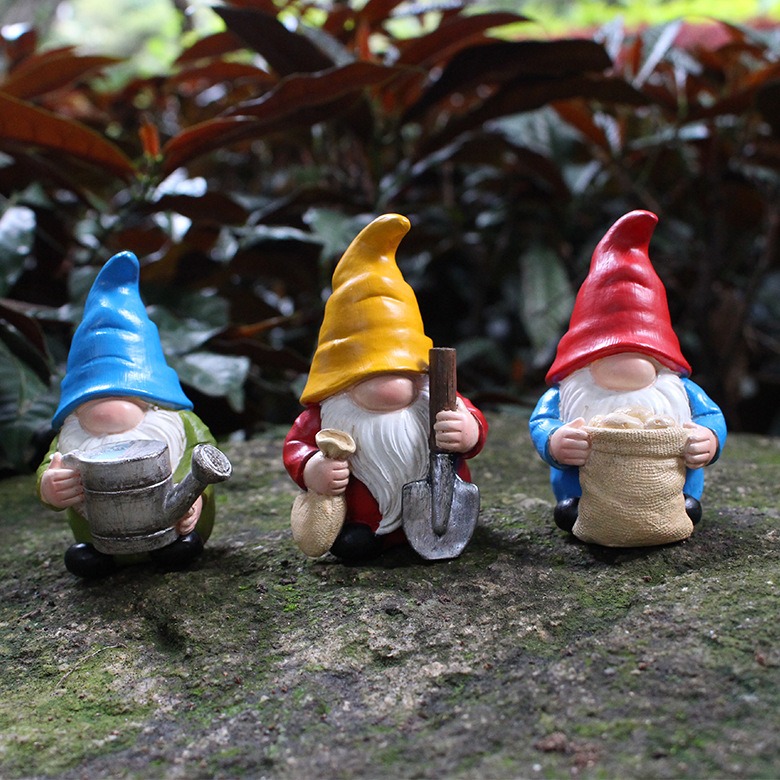Gnome figures placed among garden plants in a sunny bed